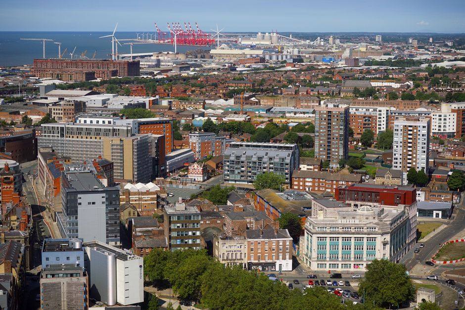 A high-angle view of a cityscape showing a mixture of residential, commercial, and industrial buildings with varied architectural styles and finishes. In the foreground, there are mid-rise and low-ris